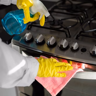Ein Ofen wird in Hygienehandschuhen mit einem Putzlappen gereinigt